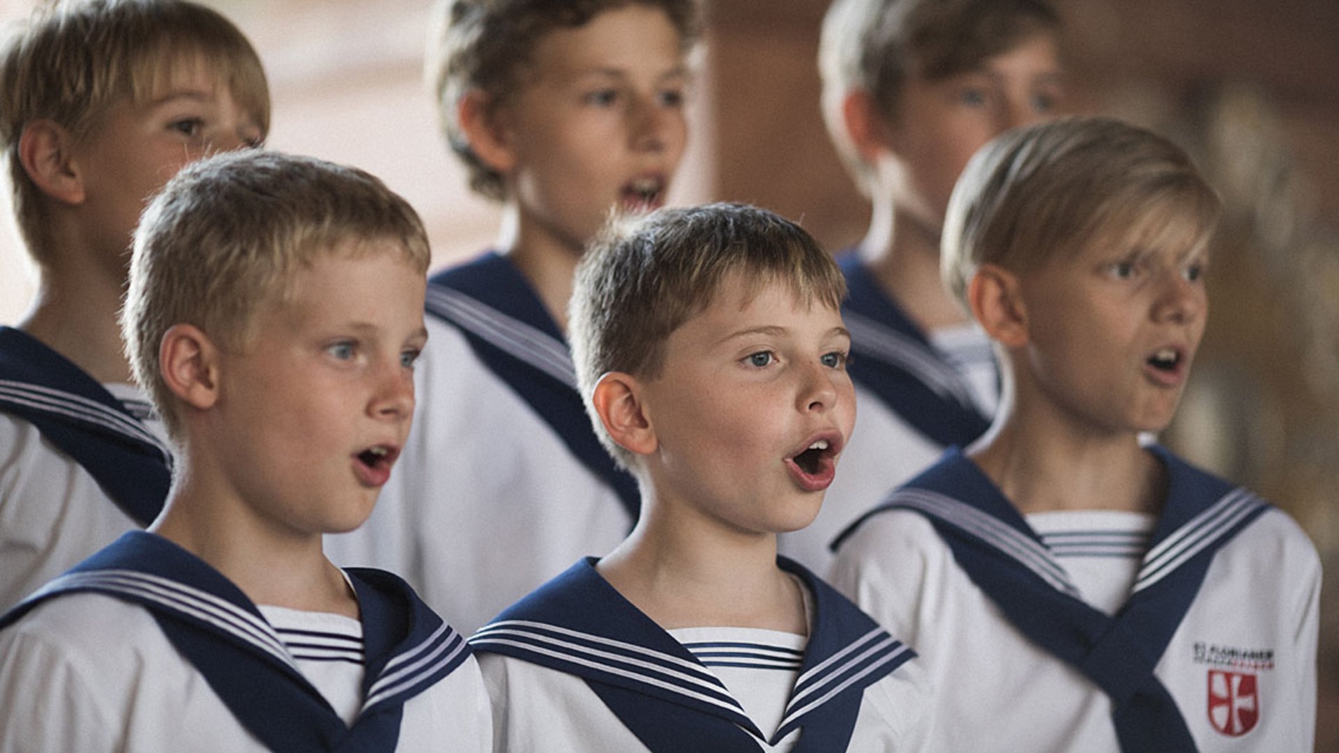 Foto Oberösterreich Tourismus GmbH/Robert Maybach: Singende St. Florianer Sängerknaben in Uniform. Sechs uniformierte St. Florianer Sängerknaben beim Singen.
