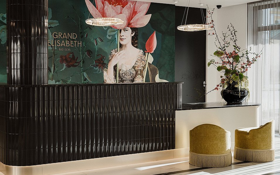 Der in Schwarz und Beige gestaltete und mit Blumen geschmückte  Rezeptionsbereich im Hotel Grand Elisabeth in Bad Ischl im Salzkammergut.