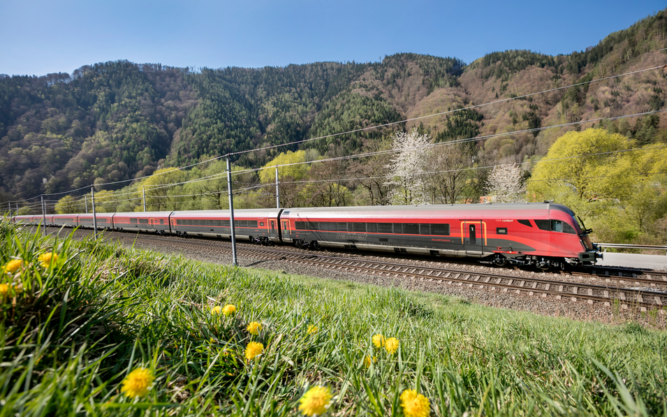 Ein Zug fährt durch die frühlingshafte Landschaft in Österreich